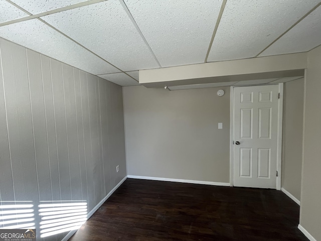 basement with dark hardwood / wood-style flooring and a paneled ceiling