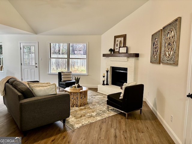 living room with lofted ceiling, a brick fireplace, and hardwood / wood-style flooring