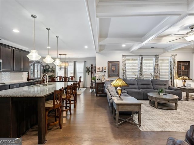 living room featuring beamed ceiling, sink, dark hardwood / wood-style flooring, coffered ceiling, and ceiling fan