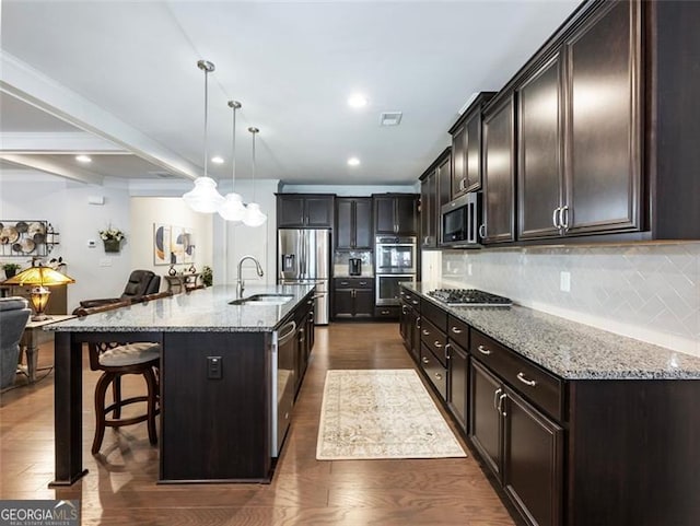 kitchen with sink, tasteful backsplash, decorative light fixtures, stainless steel appliances, and a large island