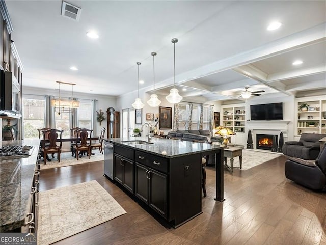 kitchen featuring a breakfast bar, sink, appliances with stainless steel finishes, an island with sink, and dark stone counters