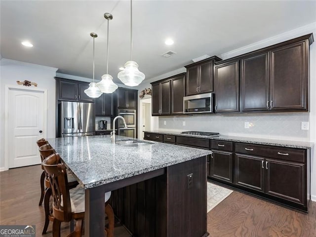 kitchen with sink, decorative backsplash, an island with sink, and appliances with stainless steel finishes