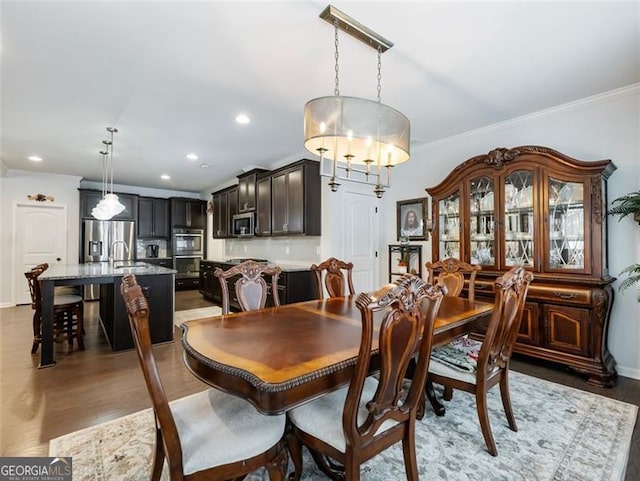 dining room with dark wood-type flooring, ornamental molding, and sink