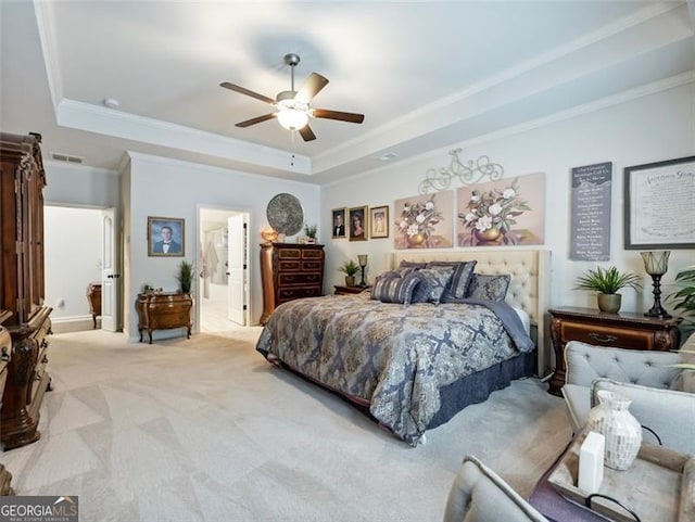 carpeted bedroom with crown molding, a raised ceiling, ceiling fan, and ensuite bathroom