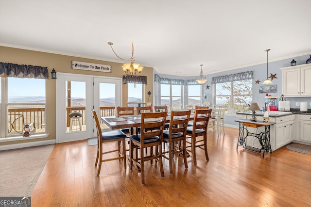 dining area with crown molding, a mountain view, light hardwood / wood-style floors, and a wealth of natural light