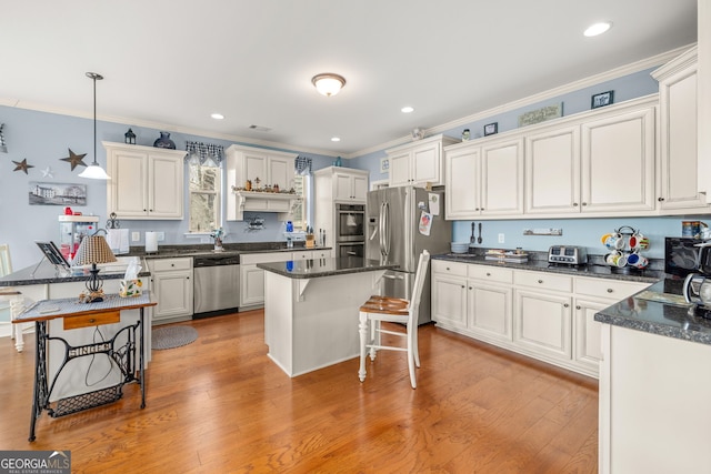 kitchen featuring appliances with stainless steel finishes, a breakfast bar, pendant lighting, white cabinets, and a center island