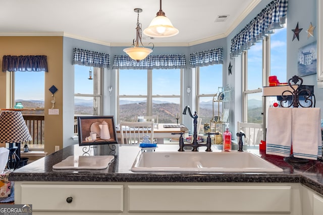 kitchen featuring crown molding, a mountain view, hanging light fixtures, and white cabinets