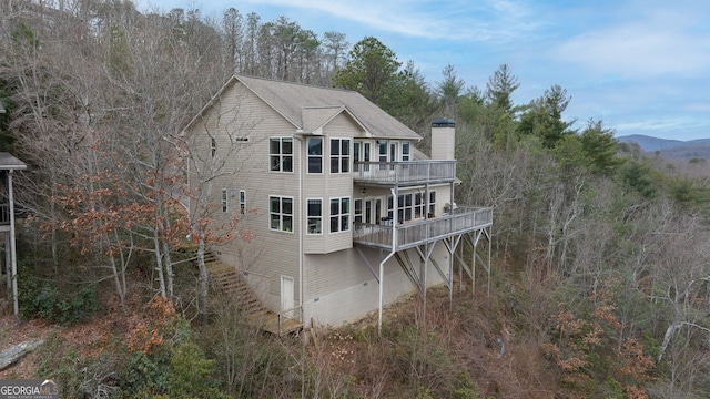 back of house with a wooden deck and a balcony