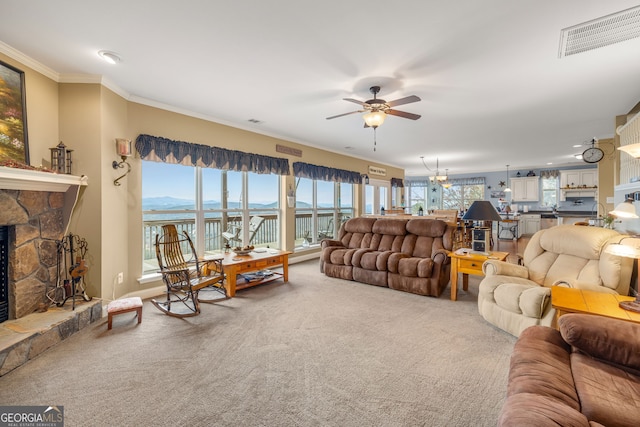 living room featuring crown molding, carpet flooring, a water and mountain view, a healthy amount of sunlight, and a stone fireplace