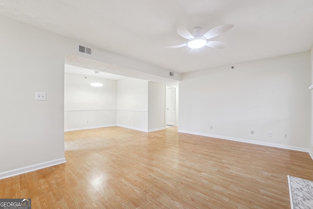 spare room with light wood finished floors, baseboards, visible vents, and a ceiling fan