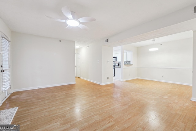 unfurnished living room with ceiling fan, light wood finished floors, visible vents, and baseboards