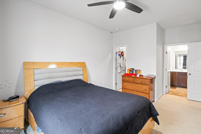 bedroom featuring ceiling fan, ensuite bathroom, and light carpet