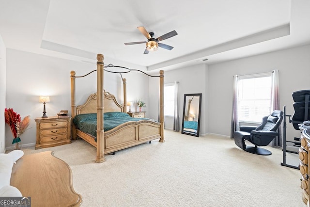 carpeted bedroom with a tray ceiling and ceiling fan