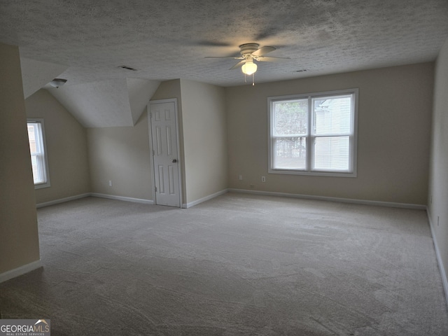 bonus room with ceiling fan, lofted ceiling, light colored carpet, and a textured ceiling