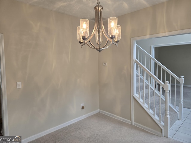 spare room with light colored carpet and an inviting chandelier