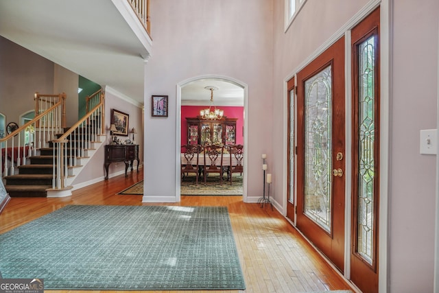 foyer entrance with an inviting chandelier, a towering ceiling, hardwood / wood-style floors, and a wealth of natural light