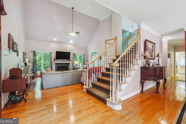 interior space with ornamental molding, wood-type flooring, high vaulted ceiling, and ceiling fan