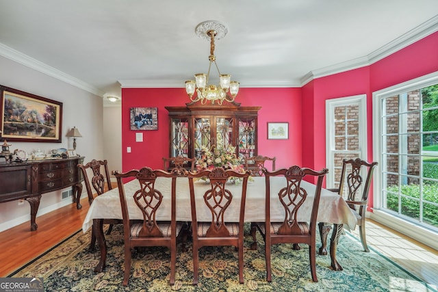 dining space with crown molding, a notable chandelier, a wealth of natural light, and wood-type flooring