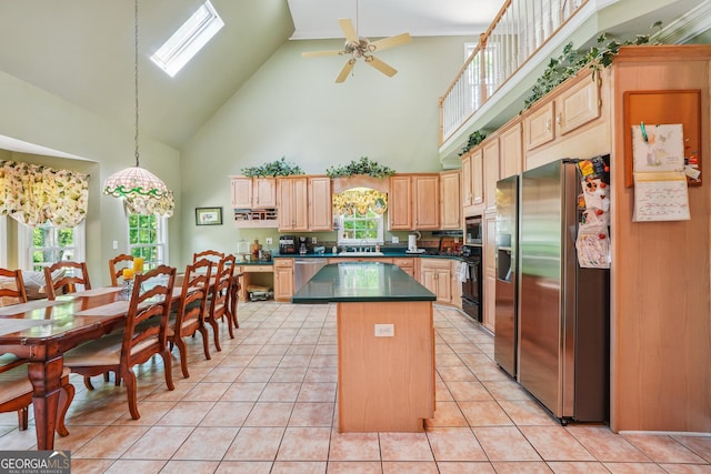 kitchen featuring light brown cabinets, light tile patterned flooring, stainless steel appliances, and a kitchen island