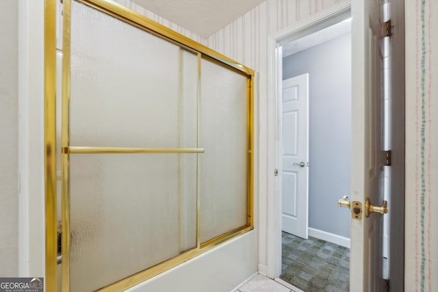 bathroom with shower / bath combination with glass door and a textured ceiling