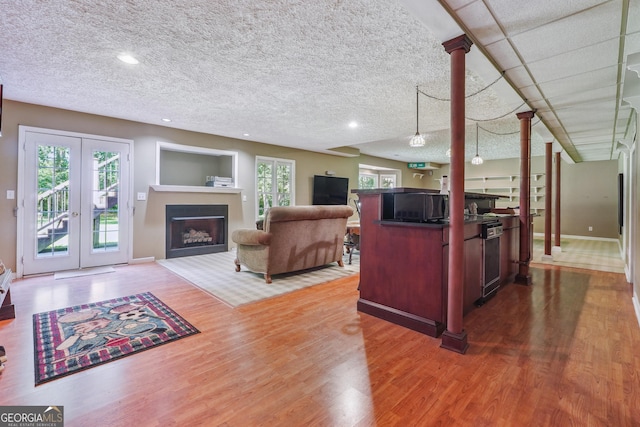 living room featuring a textured ceiling, plenty of natural light, french doors, and wood-type flooring