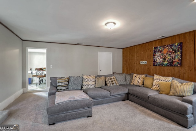 living area with visible vents, wooden walls, carpet flooring, and crown molding