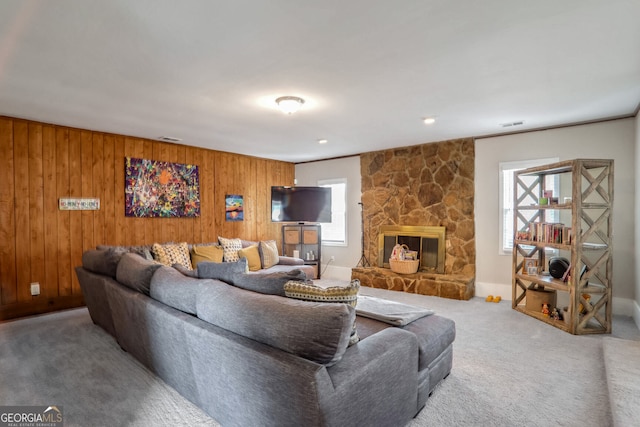 living room featuring wooden walls, carpet flooring, a fireplace, and visible vents