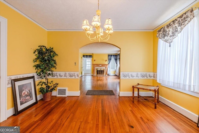 interior space featuring hardwood / wood-style flooring, ornamental molding, a textured ceiling, and a chandelier