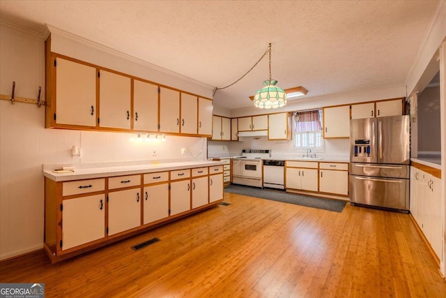 kitchen with sink, a textured ceiling, pendant lighting, white appliances, and light hardwood / wood-style floors