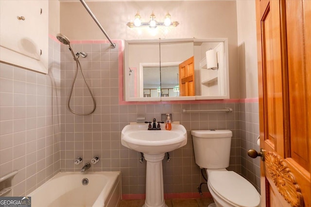 bathroom with toilet, tiled shower / bath combo, and tile walls