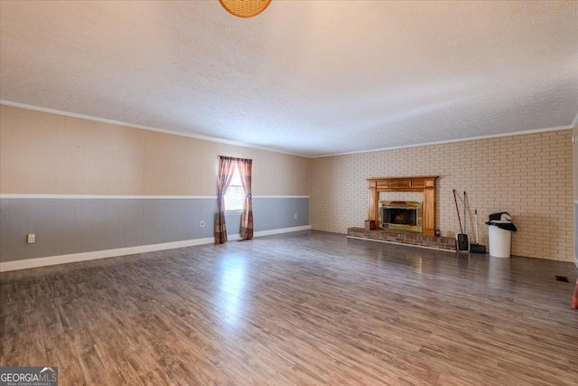 unfurnished living room featuring dark wood-type flooring, brick wall, and crown molding