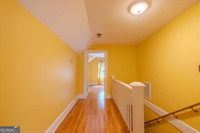 hallway with vaulted ceiling and hardwood / wood-style floors