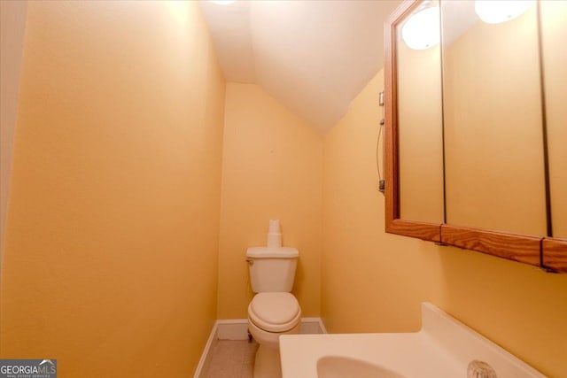 bathroom featuring vanity, toilet, and vaulted ceiling