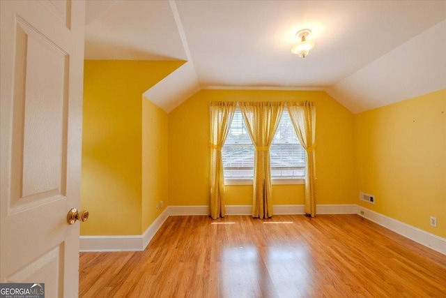 additional living space featuring vaulted ceiling and wood-type flooring