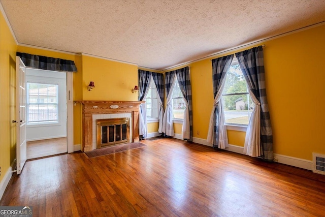 unfurnished living room featuring crown molding, a healthy amount of sunlight, hardwood / wood-style floors, and a textured ceiling