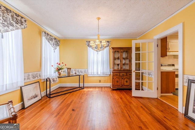 unfurnished dining area featuring an inviting chandelier, wood-type flooring, and a textured ceiling