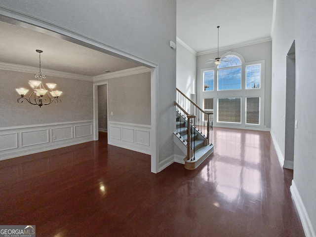 entryway with ornamental molding, ceiling fan with notable chandelier, and wood-type flooring