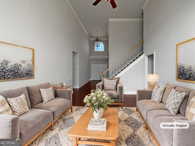 living room featuring a high ceiling, ornamental molding, wood-type flooring, and ceiling fan