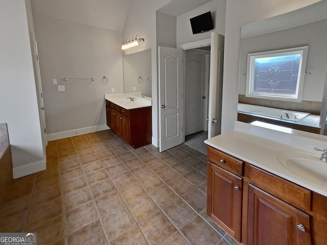 bathroom with vanity, vaulted ceiling, a bath, and tile patterned floors