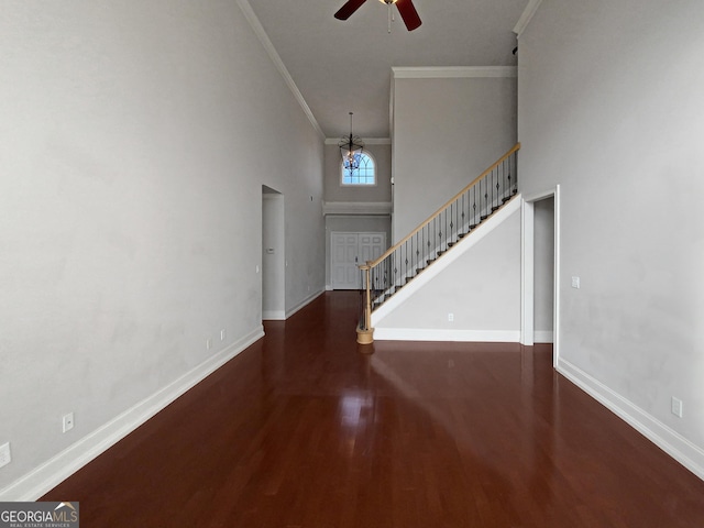 entrance foyer featuring a high ceiling, ornamental molding, dark hardwood / wood-style floors, and ceiling fan with notable chandelier