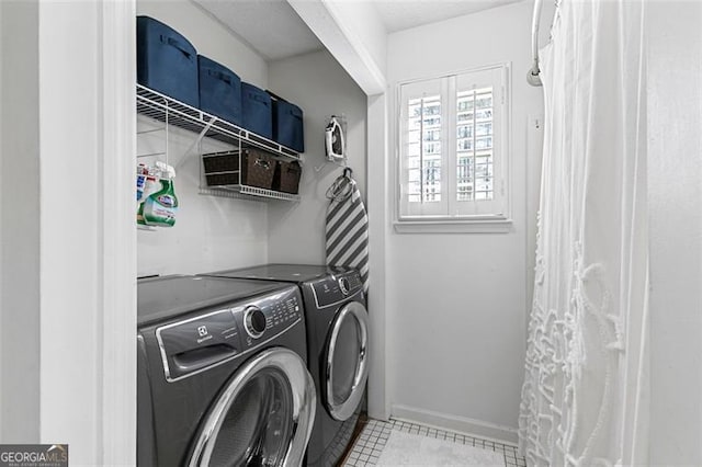 laundry area with independent washer and dryer and light tile patterned floors