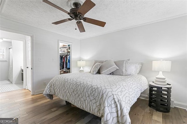 bedroom featuring hardwood / wood-style floors, a spacious closet, ceiling fan, a textured ceiling, and a closet