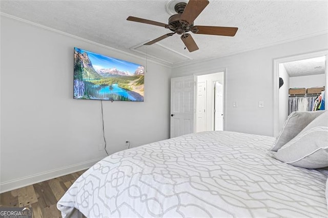 bedroom with ceiling fan, hardwood / wood-style floors, a textured ceiling, a walk in closet, and a closet