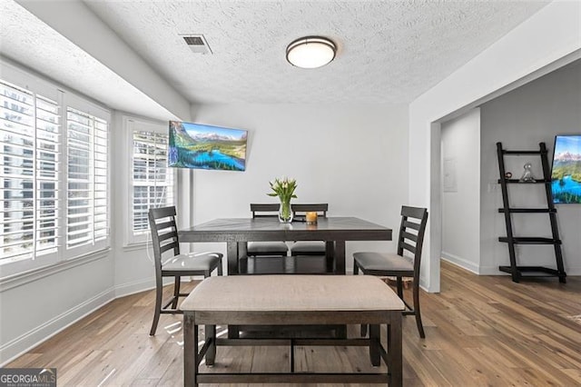 dining space with wood-type flooring and a textured ceiling