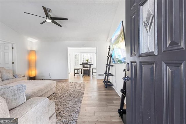 living room featuring ceiling fan, hardwood / wood-style floors, and a textured ceiling