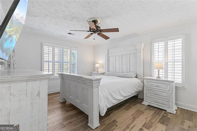 bedroom featuring ceiling fan, a textured ceiling, multiple windows, and light wood-type flooring