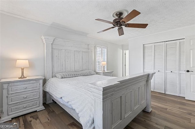 bedroom with a textured ceiling, dark wood-type flooring, a closet, and ceiling fan