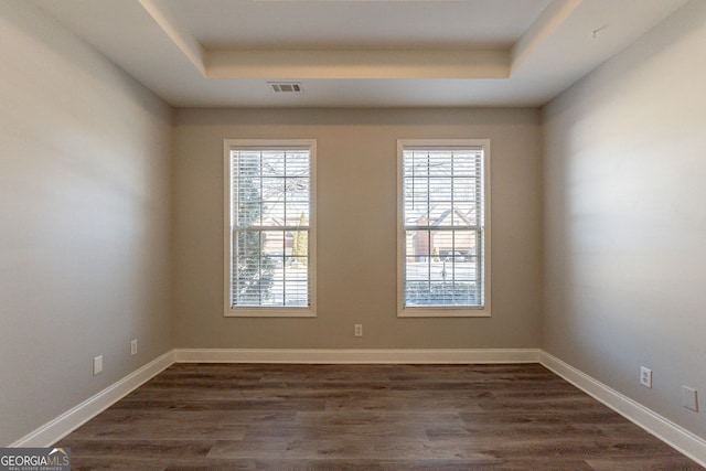 spare room with dark wood-type flooring and a tray ceiling