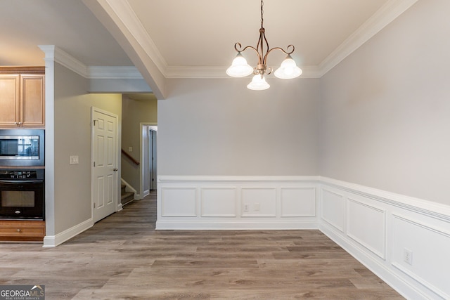 unfurnished dining area with ornamental molding, an inviting chandelier, and light hardwood / wood-style floors