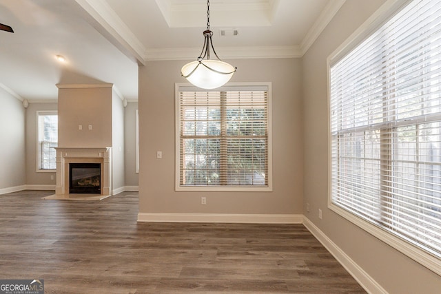 unfurnished dining area featuring ornamental molding, dark hardwood / wood-style floors, and a tray ceiling